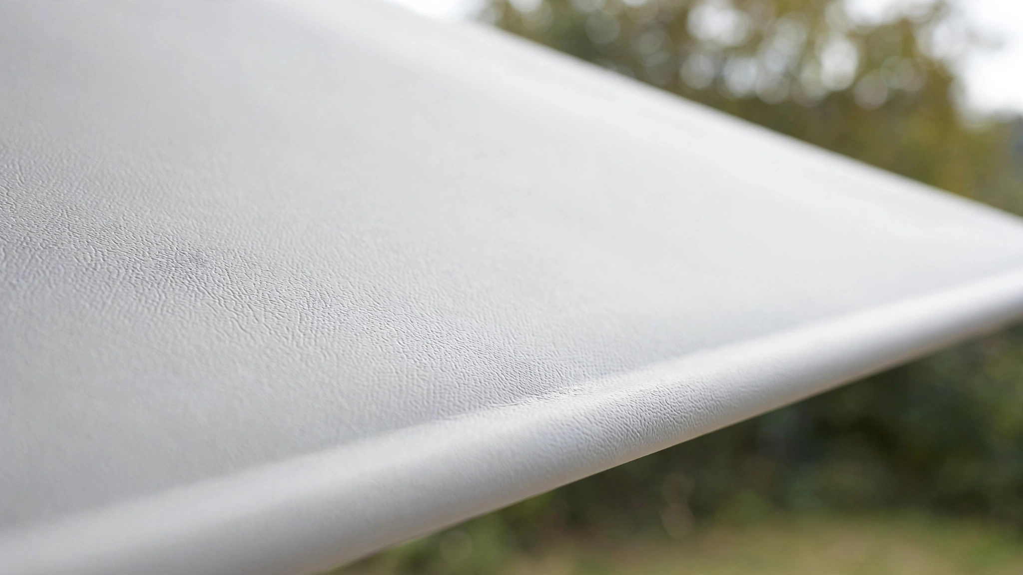Close-up of tensioned matte white projector screen material - What Projector Screen Material Is Best for Outdoors