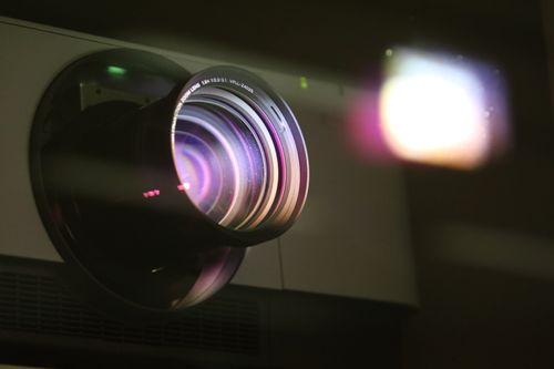 Projector lens emitting light - How Long Do Projector Bulbs Last
